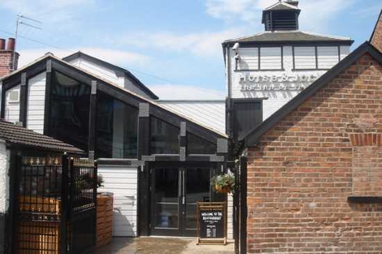 the exterior of the horse and jockey pub featuring white cladding and black glazing with exposed brickwork in the foreground